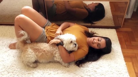Young brazilian woman playing with her dogs in the living room.