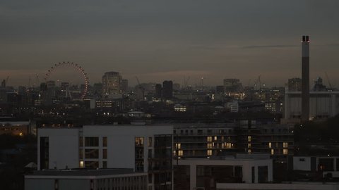 London skyline at dusk with expensive apartments in the foreground. London Eye and the Wembley Stadium can be seen in the distance.
