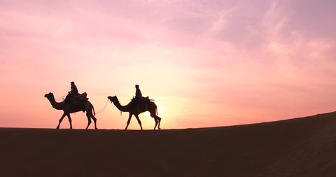 Silhouette of the Camel Trader crossing the sand dune during sunrise at Thar Deset in Jaisalmer, India. Image is soft and contain noise due to high ISO used.