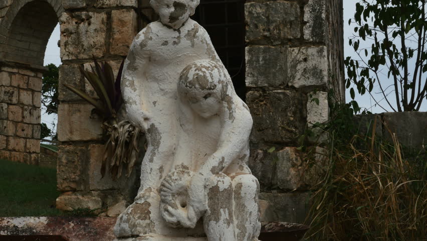 P1060365-Tilt up-Aging weathered white-washed statues and stone structure in Columbus Park in DISCOVERY BAY, Jamaica. This historic open-air museum sits by the side of road in this north coast town