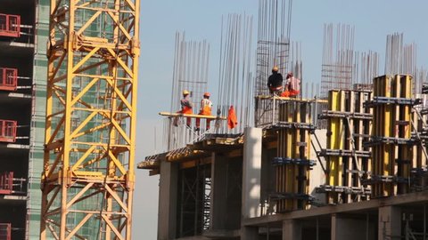 Workers on building carcass, blue sky at background 