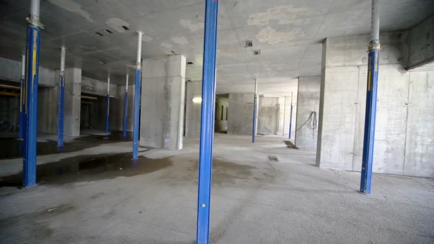 Worker walk inside dark unfinished room at construction site
