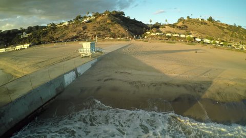 Flying low over Malibu beach around lifeguard tower in Los Angeles at sunset