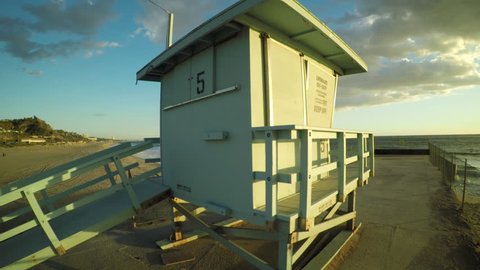 Flying away from a life guard tower at Malibu beach in Los Angeles during sunset hour