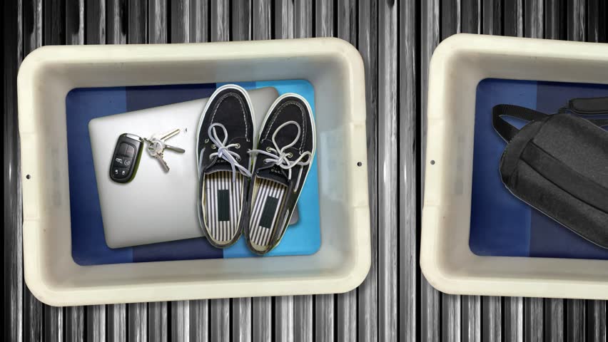 Various personal items from passengers pass by in bins on their way into the x-ray machine at an airport security checkpoint station.	