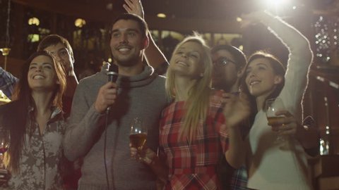 Friends are singing karaoke songs while having a good time together at a bar. Shot on RED Cinema Camera in 4K (UHD).