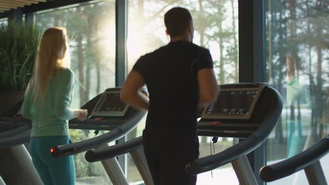 Young athletic men and women exercising and running on treadmill in sport gym. Shot on RED Cinema Camera in 4K (UHD).