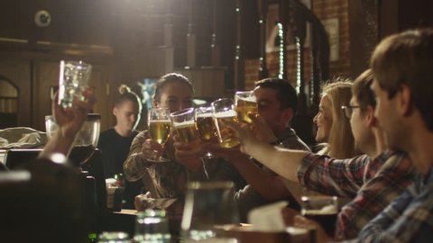 Friends do toasts, drink beer and cocktails while having a good time together at a bar. Shot on RED Cinema Camera in 4K (UHD).