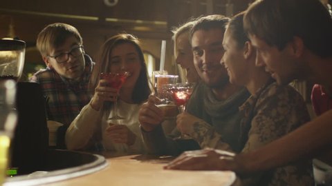 Friends laugh, drink beer and cocktails while having a good time together at a bar. Shot on RED Cinema Camera in 4K (UHD).