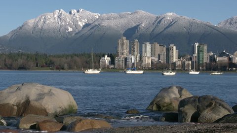 Vancouver Towers, Mountain Snow, English Bay Shore. Sailboats anchored in English Bay in the early morning. North Shore Mountains. Vancouver, British Columbia, Canada. 4K. UHD.
