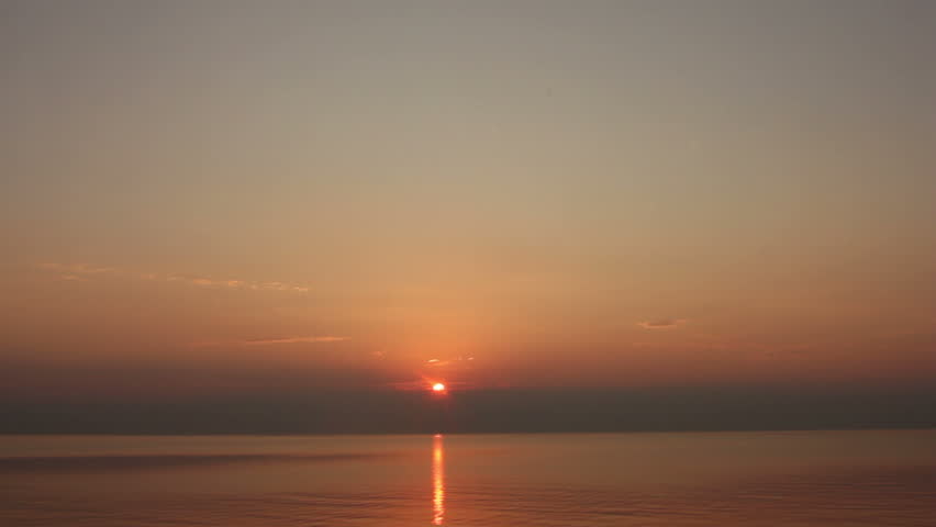 Last bits of sun is setting over water with gentle waves. Fast forward time lapse clip.