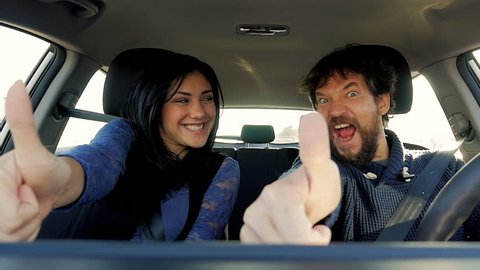 Man and woman making ok sign while driving car