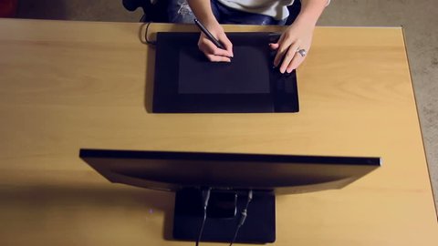 Stock footage of a young female designer working in her office with graphics tablet creating digital art