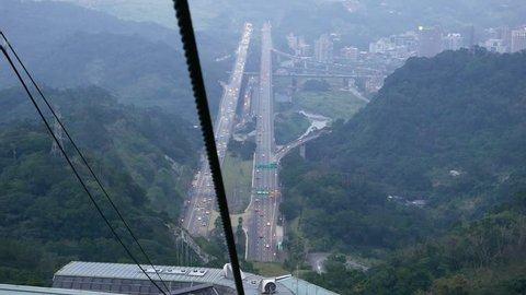 Approaching to Maokong gondola lift middle station, Formosa freeway aerial perspective in dusk. Shoot from cabin move down, evening time. Mountain landscape in twilight.