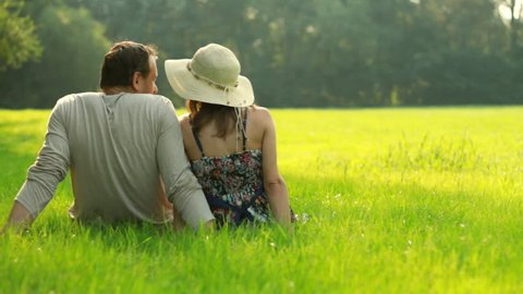  Couple sitting on meadow and looking at the landscape 