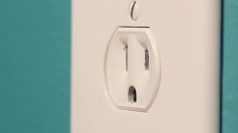 Macro footage of a 2 prong American electrical plug being unplugged and plugged back into a power receptacle (outlet).