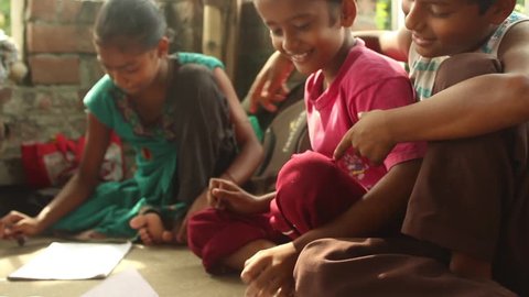 Simple, sweet Indian boys and girls laugh and draw happily with each other in a rural school in Bengal