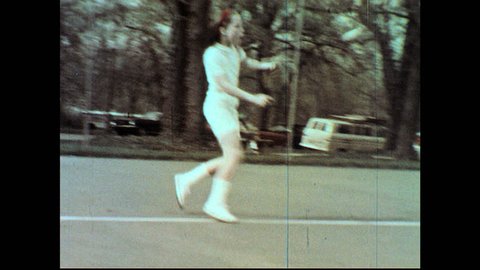 UNITED STATES 1960s: Panning shots, girl playing tennis / Teen girl playing tennis, misses ball / Boys laugh / Girl swings at ball, rubs knee.