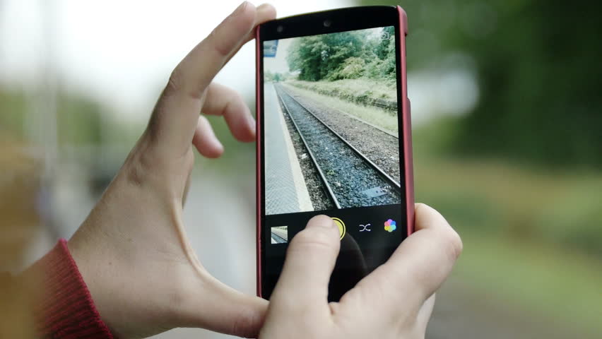 hands of woman using smartphone to make pictures of railtracks, railway