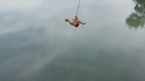 High angle wide shot of man swinging into lake / Mona, Utah, United States