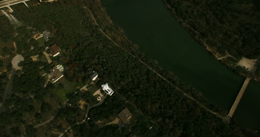 The camera slowly tilts up and moves forward to reveal Mansfield Dam in Austin, Texas.  Traffic is seen crossing the bridge that runs parallel to the dam.