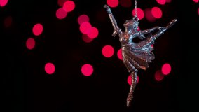 Keychain ballerina swinging on a chain on the background of beautiful christmas bokeh.