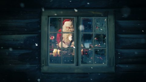 Santa seen through the frozen window preparing gifts for kids. Snowing.