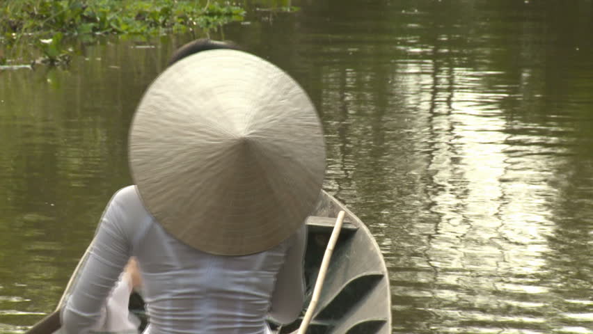 A lady is rowing traditional boat in river in Vietnam