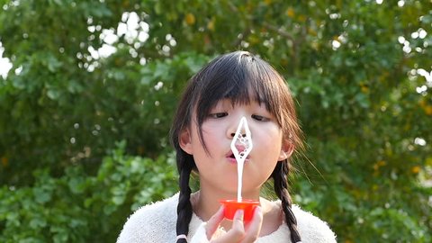 Cute asian girl is blowing a soap bubbles Stockvideó