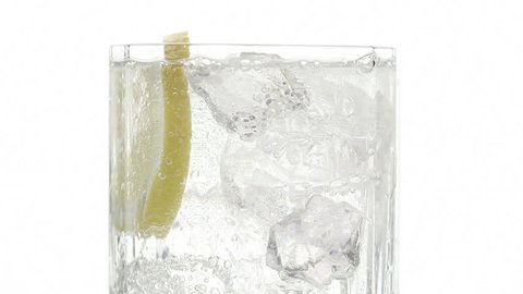 Close up of Glass with Ice Cubes, sparkling water and a lemon Wedge