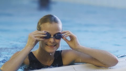 Happy Professional Female Swimmer in Goggles Getting out the Water in Swimming Pool. Shot on RED Cinema Camera in 4K (UHD).