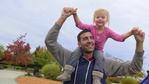 Cute little girl acts like superwoman flying on her dads shoulders