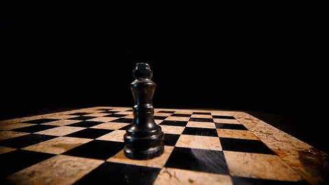 4K footage of a chess board on a black background with a black king on it, a white king hits the black and stands on his place...