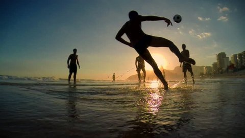 Silhouettes of carioca Brazilians playing altinho beach football at sunset on Ipanema Beach in Rio de Janeiro, Brazil