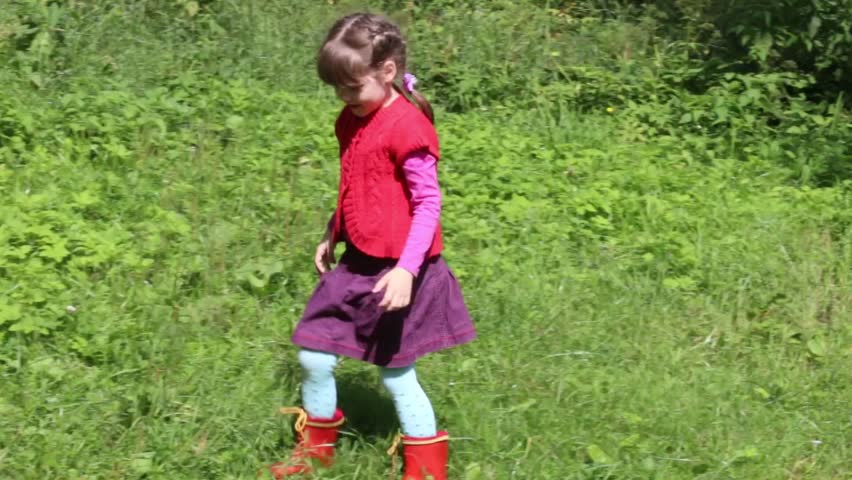 Little cute girl playing on green grass with orange ball