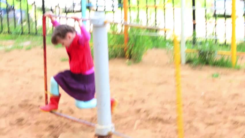 Little cute girl spinning quickly on playground at summer day
