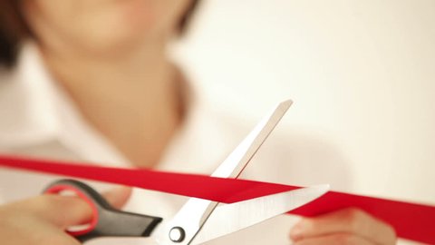Business woman cutting the red ribbon with scissors and opens the event