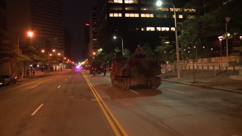 CIRCA 2010s - Police and Marines roll out tanks and armored vehicles through an American city during times of public unrest and rioting.