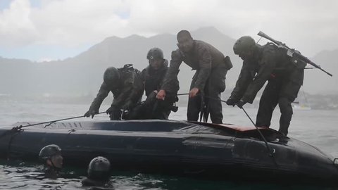 CIRCA 2010s - Navy Seals train on rubber zodiac watercraft while a helicopter performs a helicasting maneuver.