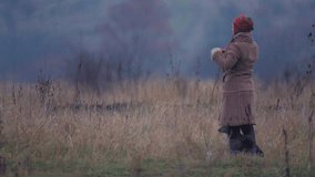 Young woman with a dog for a walk. Young girl with a dog in the field. Young woman in warm clothes in a field. 