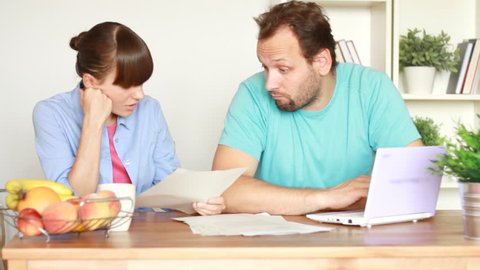 Worried couple calculating their bills by the table at home