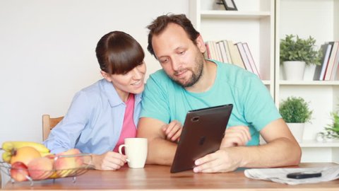 Young couple chatting on tablet computer by the table