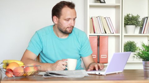Portrait of young man drinking coffee, tea and working on laptop