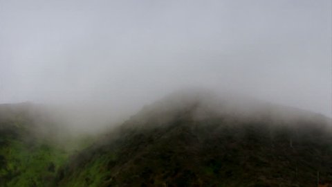 Heavy mist floats through coastal hills.