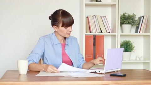 Woman calculating her bills by the table at home
