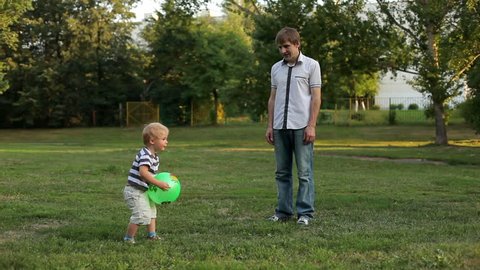 Father and son playing ball in the meadow 