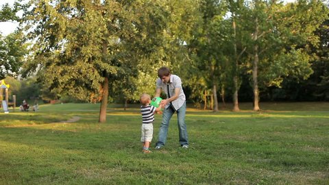 Father and son playing ball in the meadow 