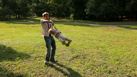 Father spinning his son in a meadow on a sunny day 