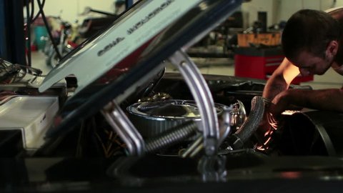 Man working on the engine of a classic car in a shop