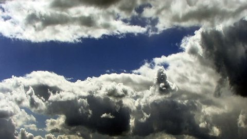 Time lapse rain clouds roil in a deep blue sky.